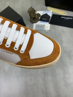Close-up of brown suede and white sneakers with textured panel and lace eyelets.