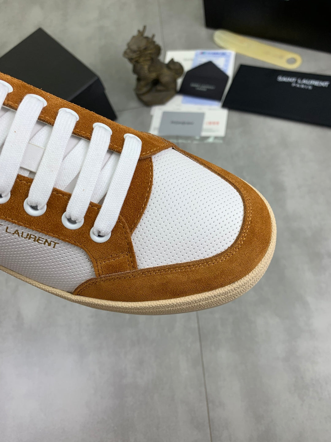 Close-up of brown suede and white sneakers with textured panel and lace eyelets.