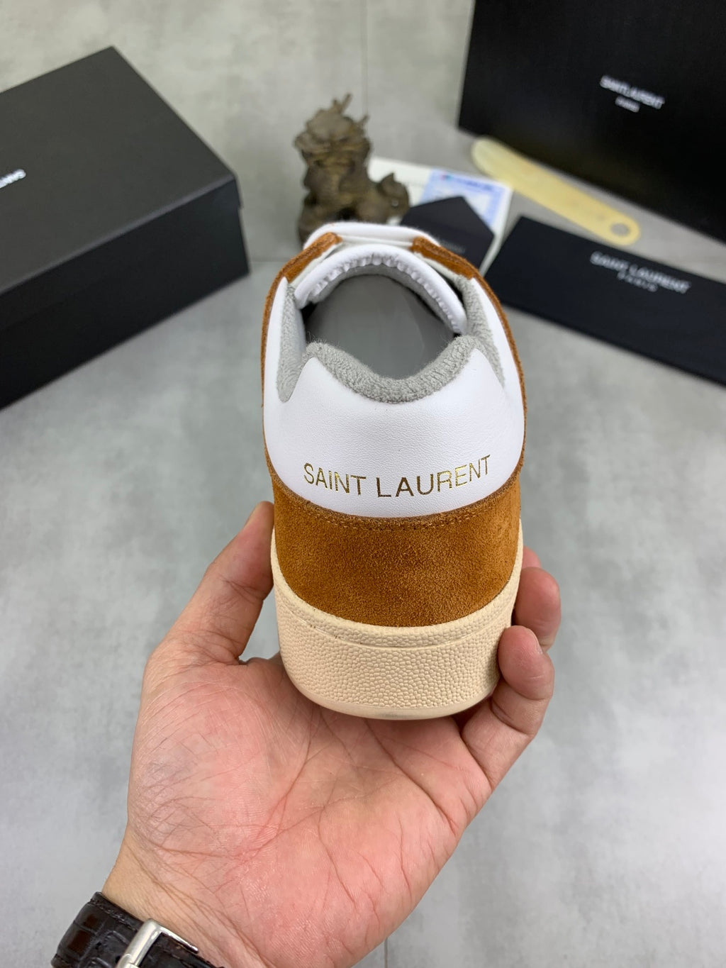 Back view of brown suede and white sneakers with SAINT LAURENT on heel tab.