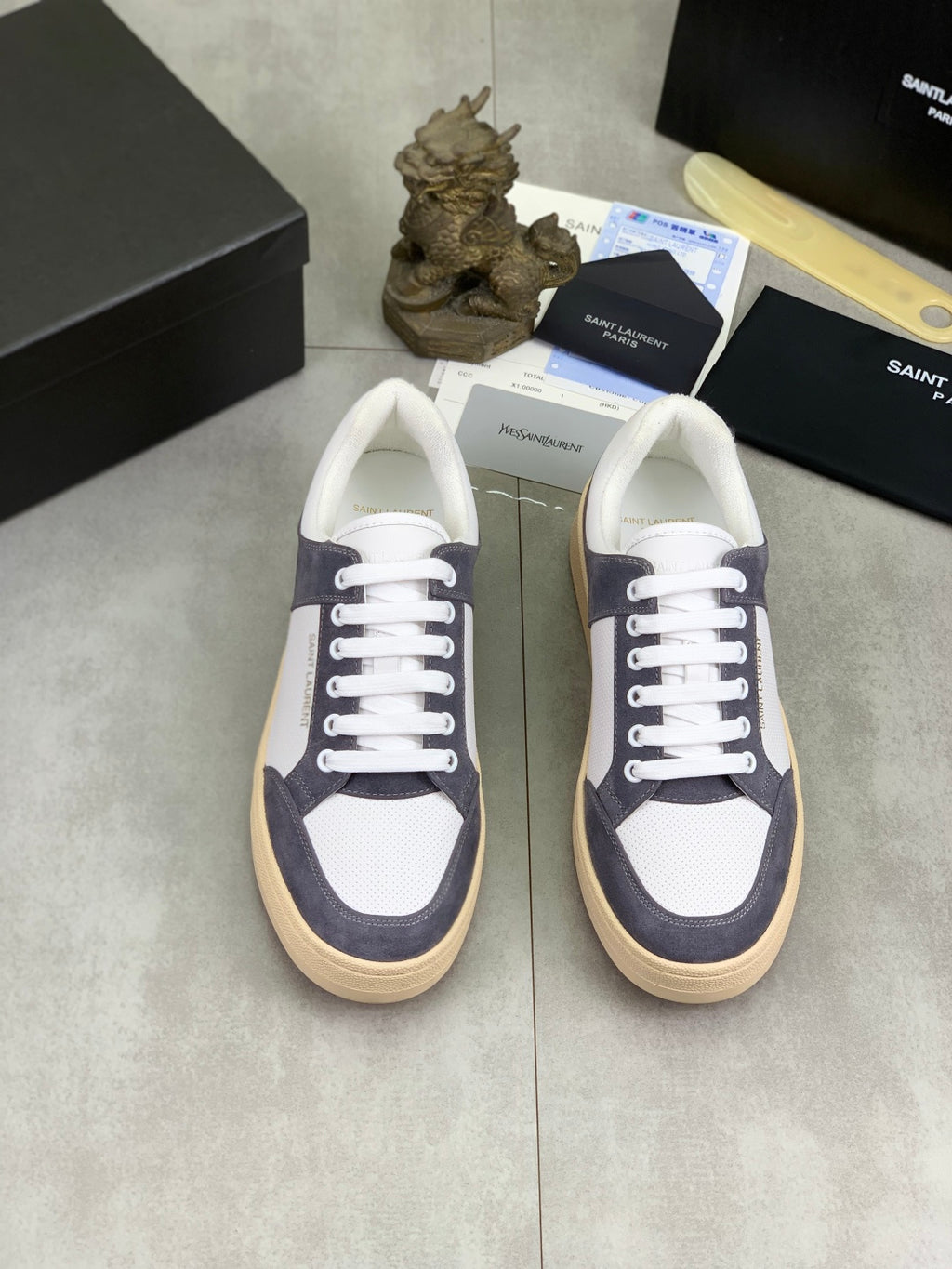 Low-top sneakers pair with white uppers and navy suede panels, white laces, gum soles.