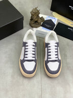 Low-top sneakers pair with white uppers and navy suede panels, white laces, gum soles.