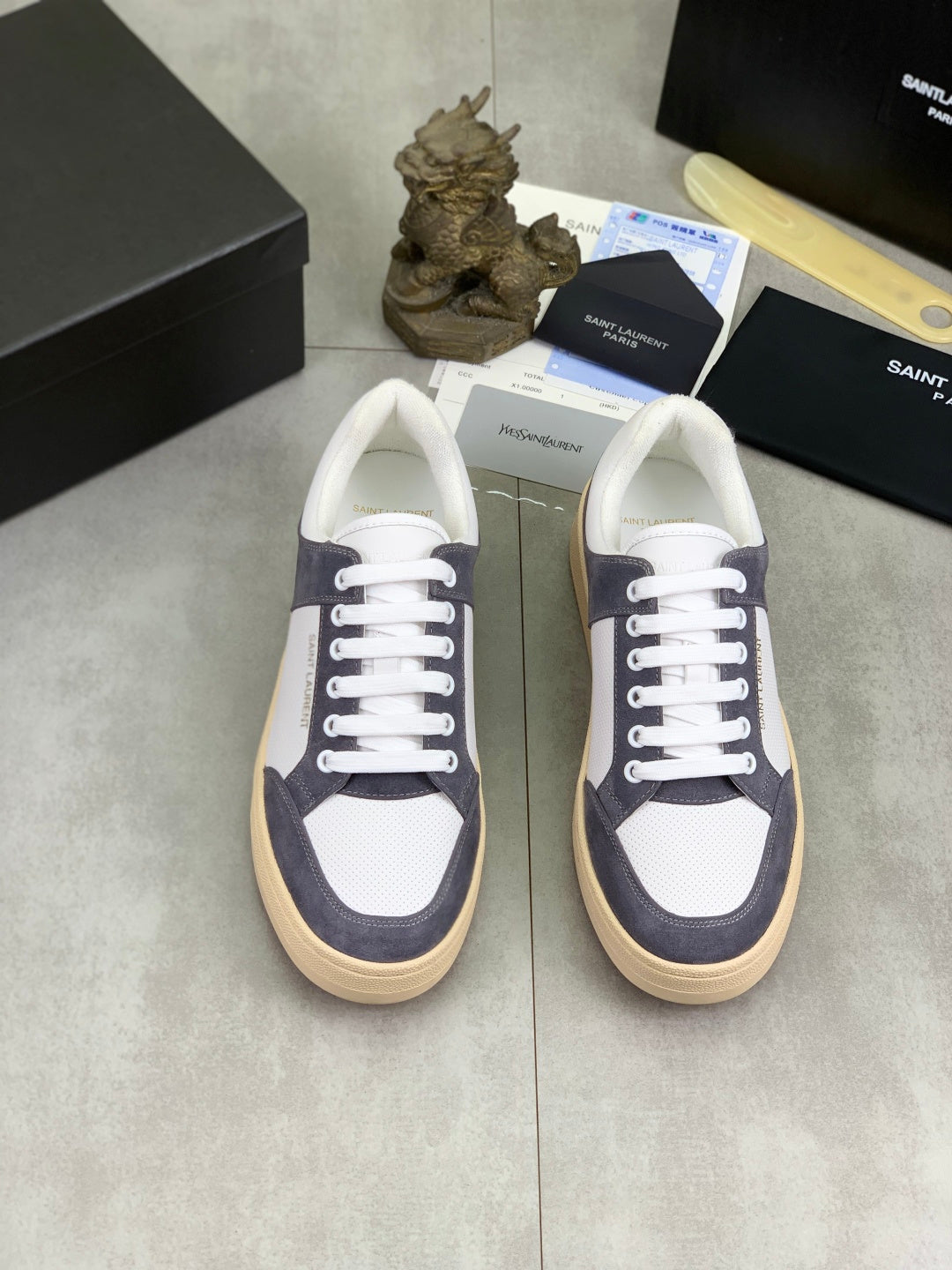 Low-top sneakers pair with white uppers and navy suede panels, white laces, gum soles.