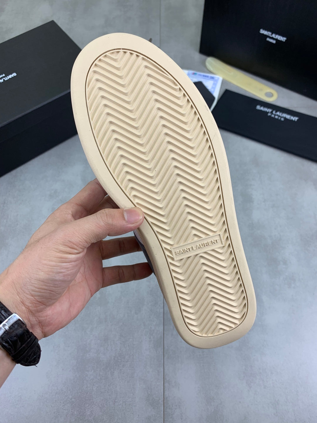Rubber outsole of low-top sneakers, cream tread with chevron pattern.