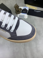 Low-top sneaker toe detail: white perforated fabric, navy suede, gum trim.