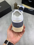 Low-top sneakers heel view, white leather with navy suede, cushioned collar, gum sole.