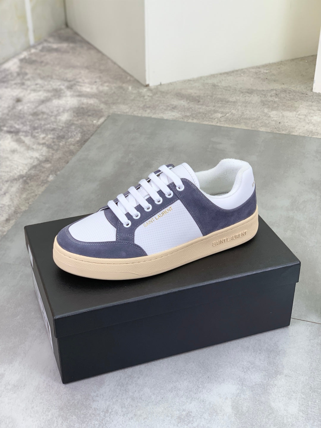 Low-top sneakers in navy and white with white laces and cream/tan sole edge.