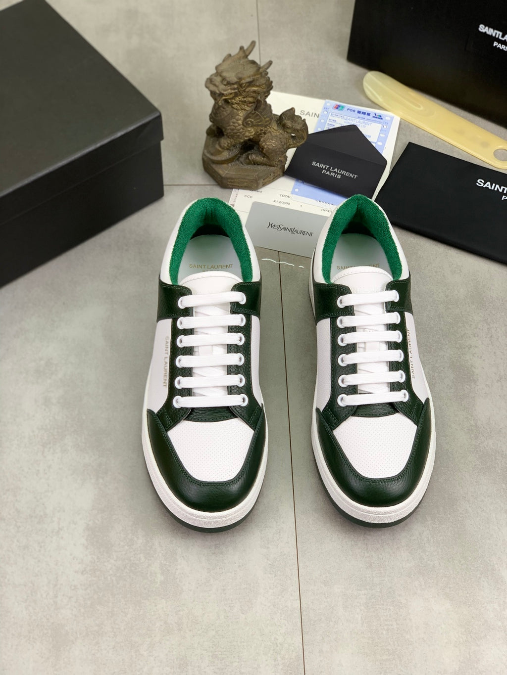 Luxury shoes pair: white uppers with dark green panels, white laces, low-profile sole