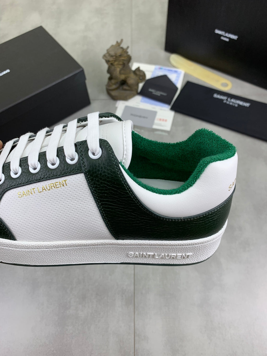 Luxury shoes close-up: white laces on dark green panel with Saint Laurent branding