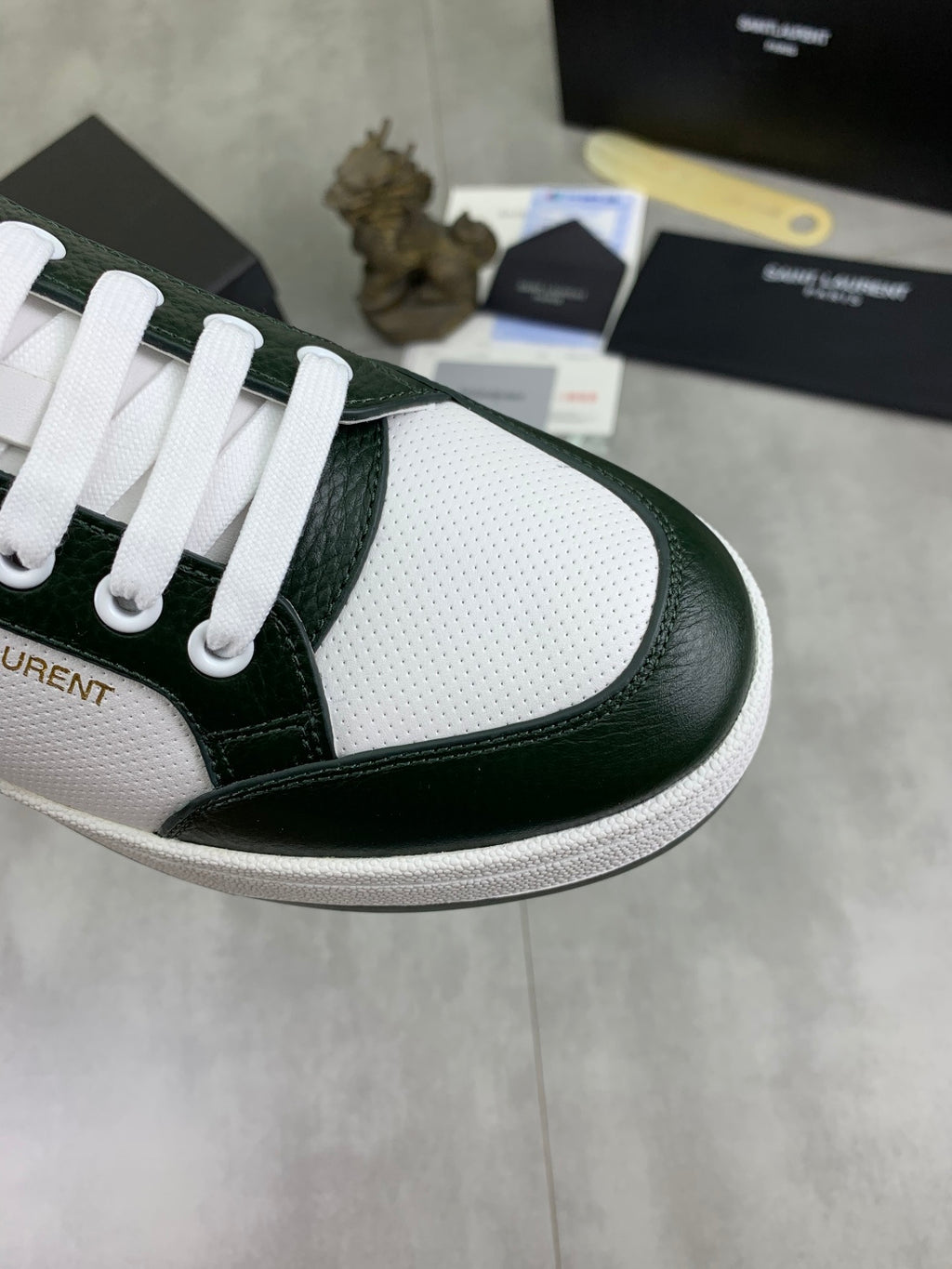 Luxury shoes close-up: white perforated toe with dark green leather side and white laces