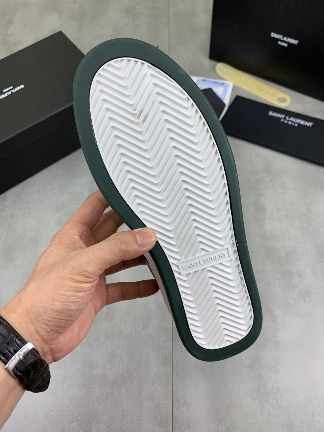 Luxury shoes outsole view with dark green edge and white chevron tread
