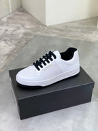 White low-top sneakers with black lace-up, side profile on a shoe box