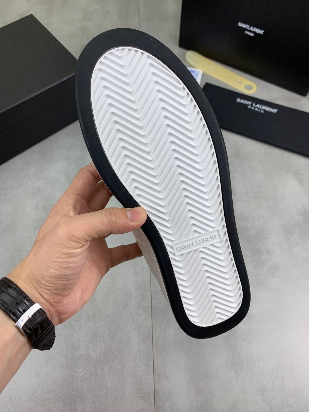 White sneaker outsole view with black edge and herringbone tread