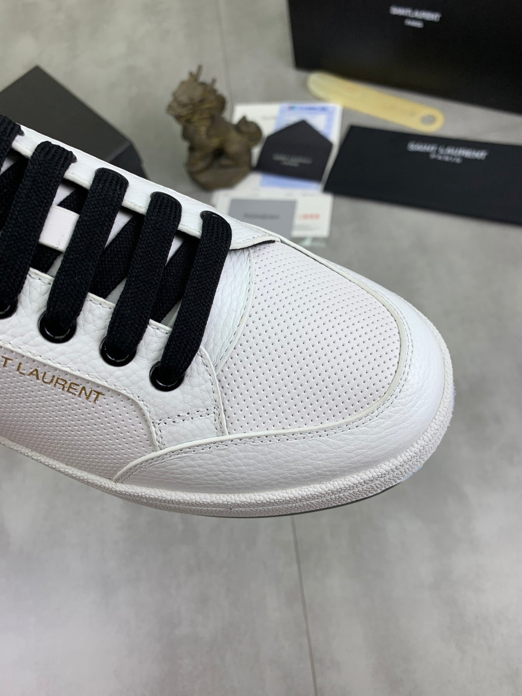 White low-top sneaker with black laces and textured toe panel detail