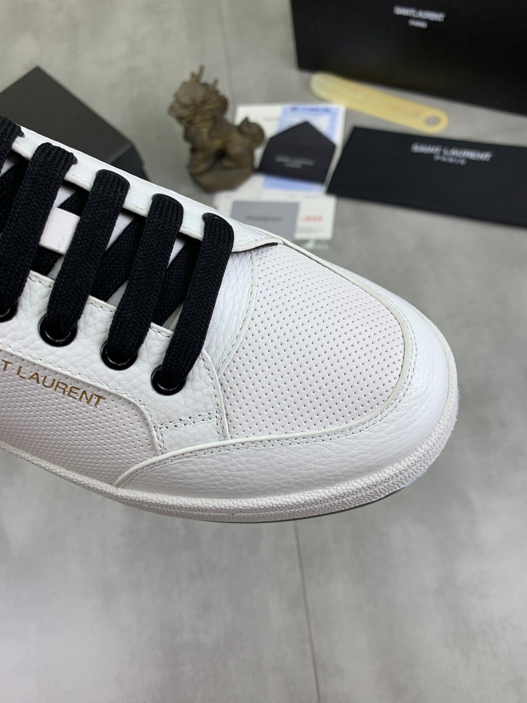 White low-top sneaker with black laces and textured toe panel detail