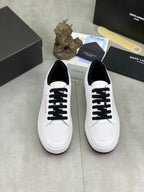 Pair of white low-top sneakers with black laces on a display surface