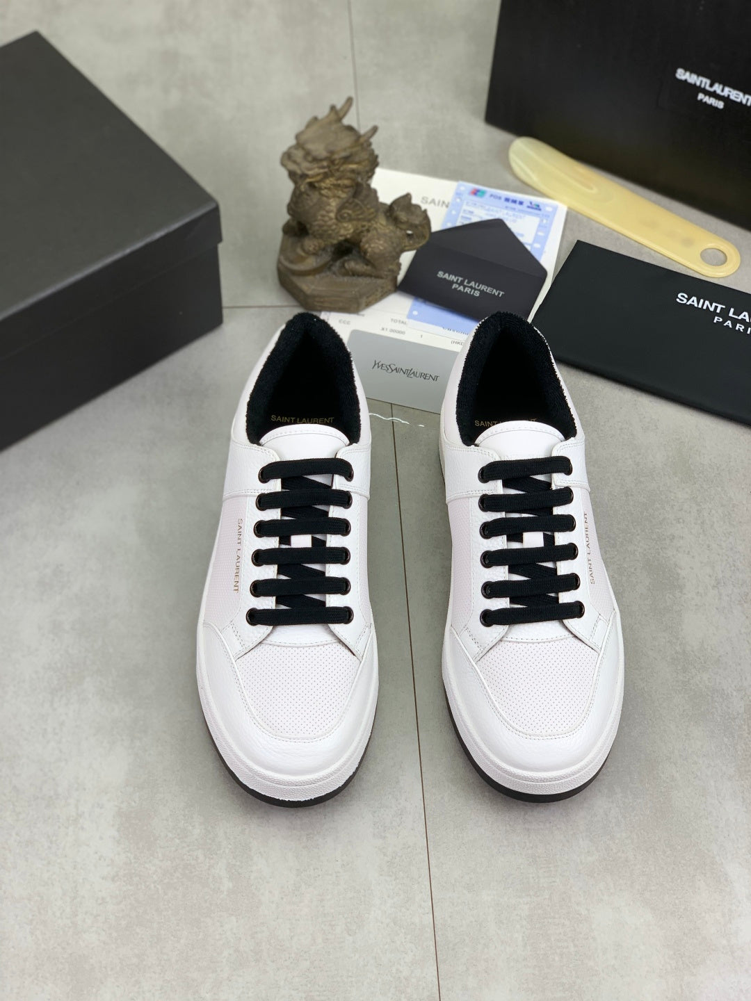 Pair of white low-top sneakers with black laces on a display surface