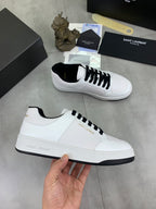 White low-top sneakers with black laces, held in hand for side view