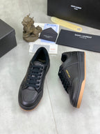 Black lace-up sneakers with textured upper and gum-brown outsole