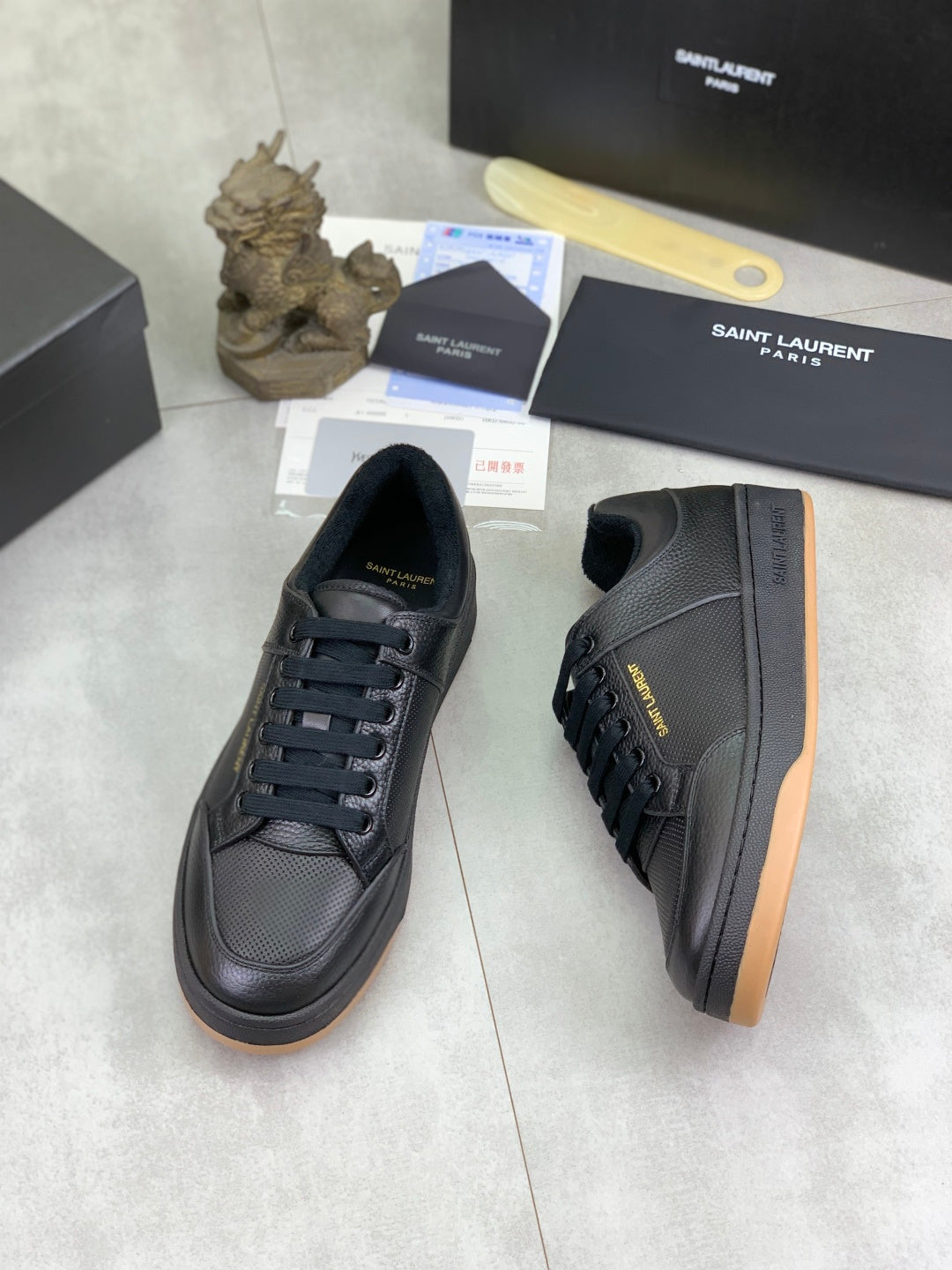 Black lace-up sneakers with textured upper and gum-brown outsole