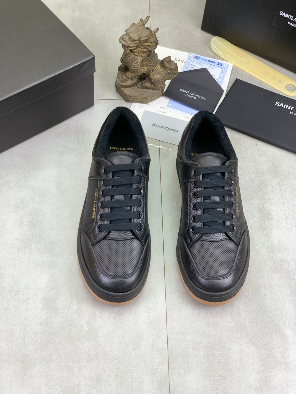 Pair of black lace-up sneakers with textured finish and gum-brown sole edge