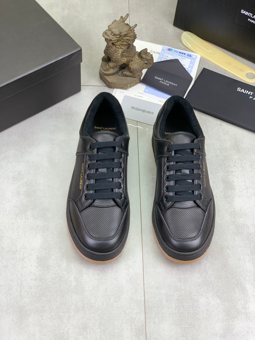 Pair of black lace-up sneakers with textured finish and gum-brown sole edge
