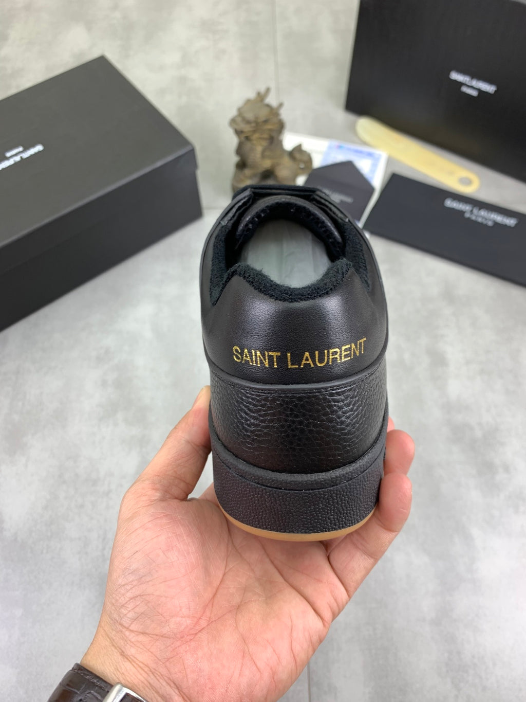 Back view of black lace-up sneakers with branded heel and gum-brown sole