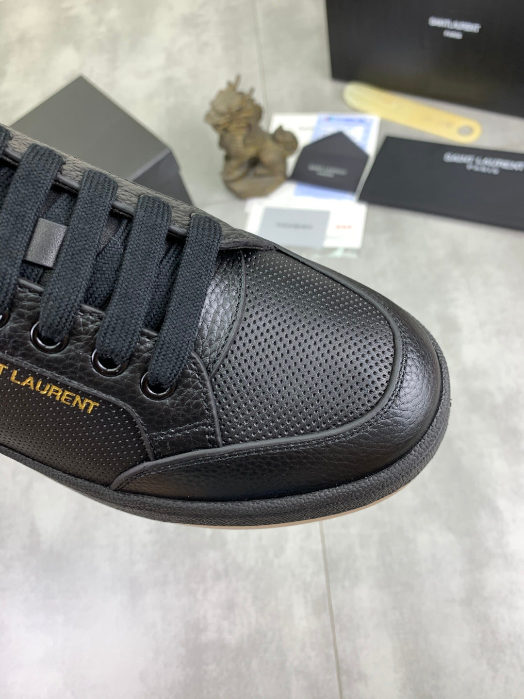 Black lace-up sneaker with perforated-texture side panel and dark rubber sole