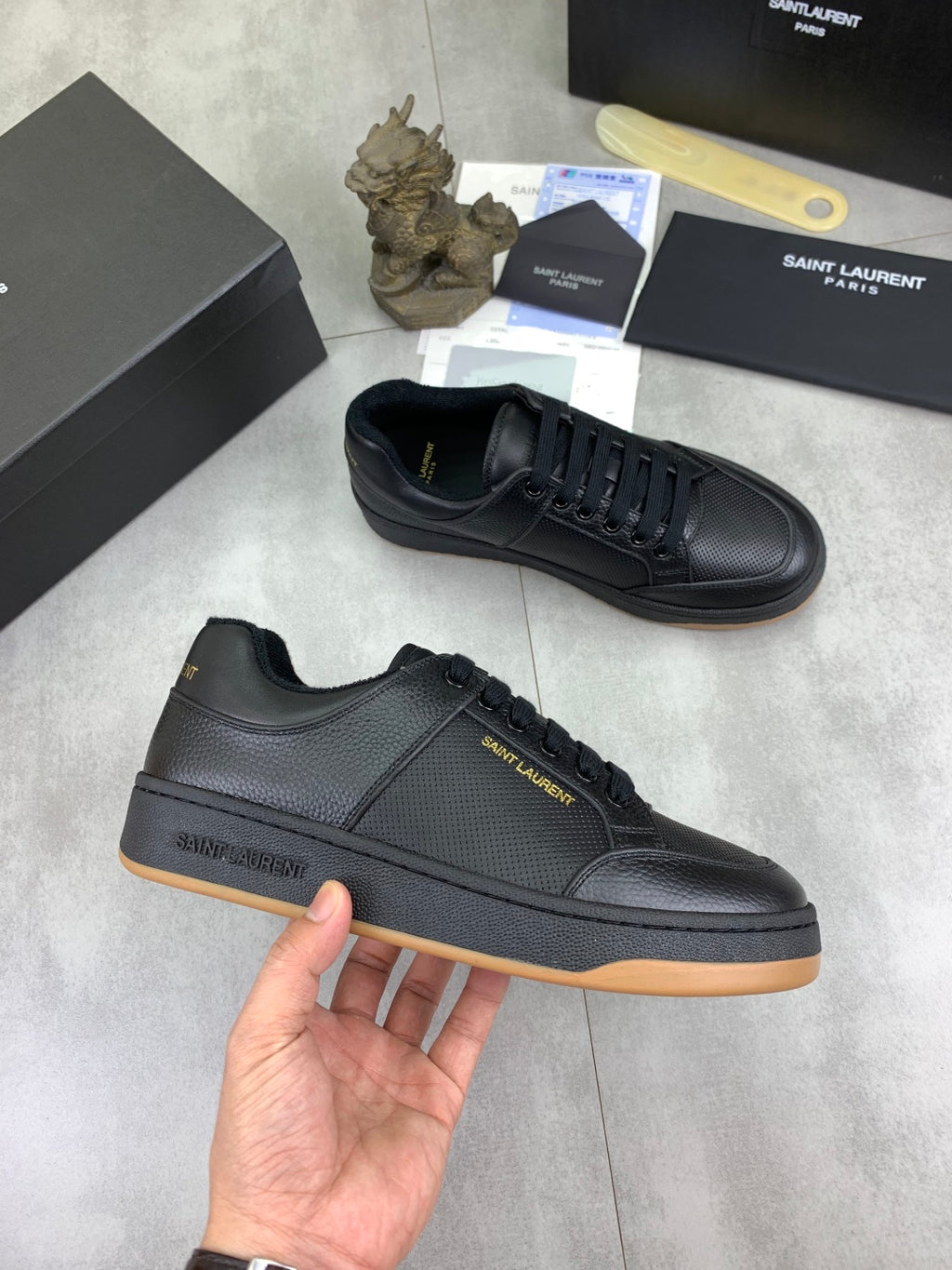 Black lace-up sneakers with textured upper and gum-brown outsole edge