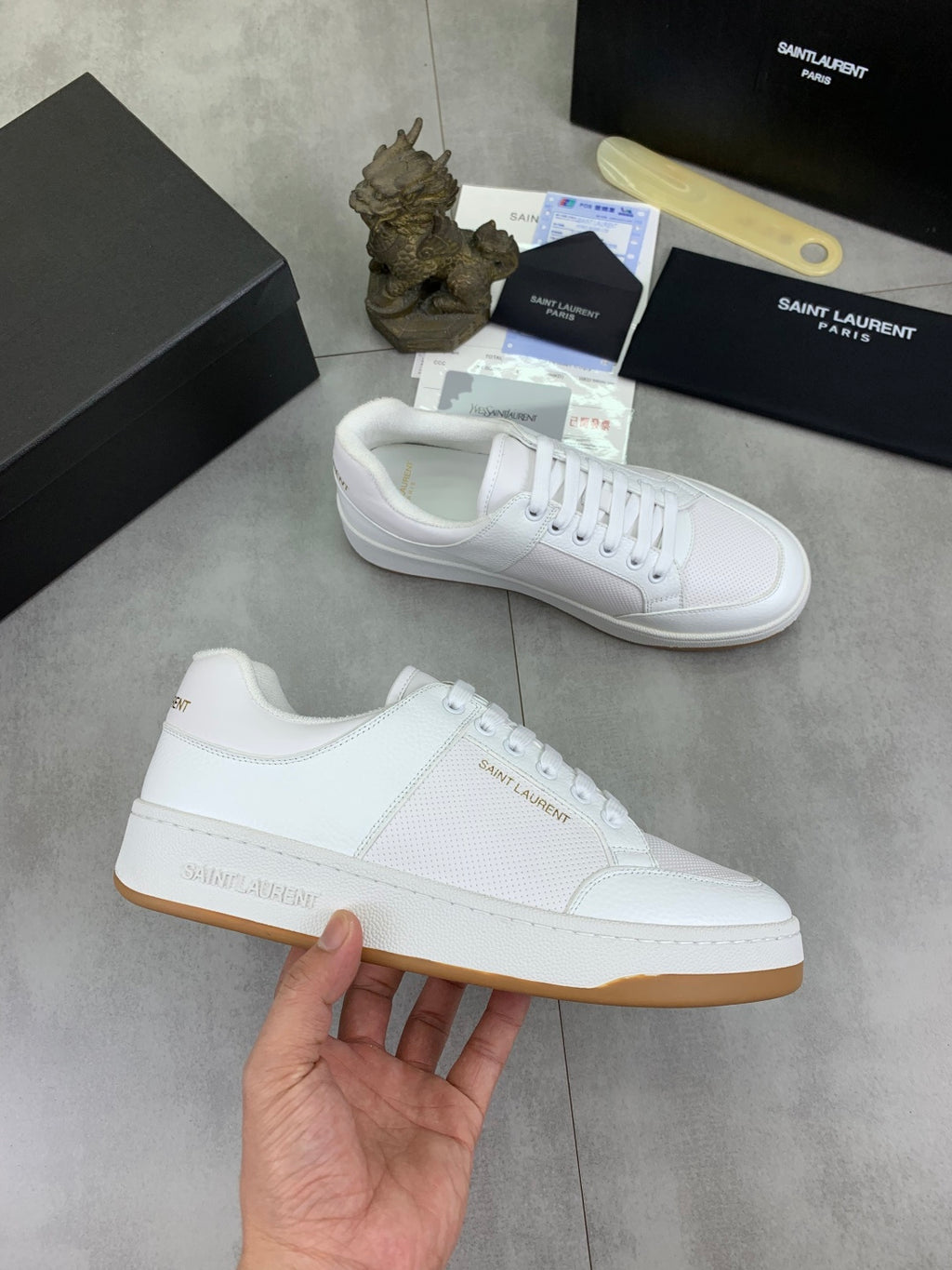 White low-top lace-up sneakers with gum-style sole in hand
