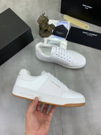 White low-top lace-up sneakers with gum-style sole in hand