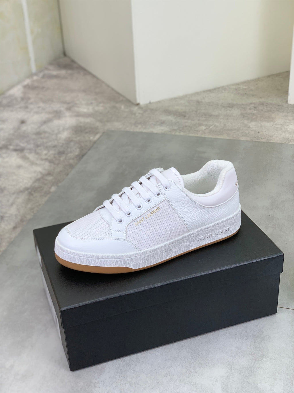 White low-top lace-up sneaker on black box with gum-style outsole