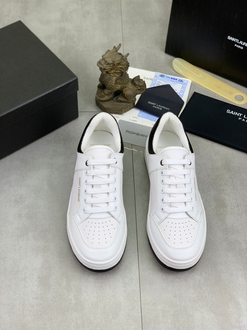 Pair of white unisex low-top sneakers with perforated toe and lace-up front