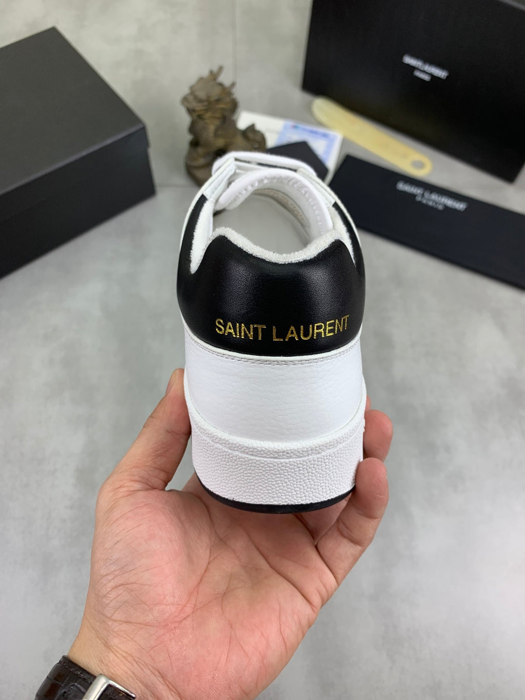 Back view of white unisex sneakers with black heel panel and lace-up closure