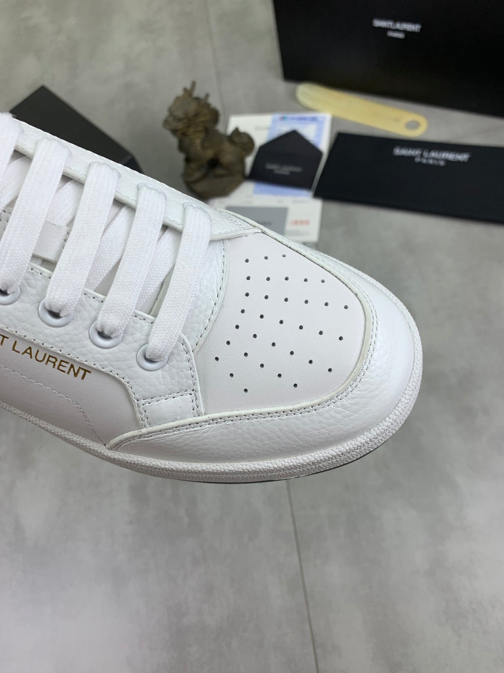 White unisex sneaker with perforated quarter panel and white lace-up closure