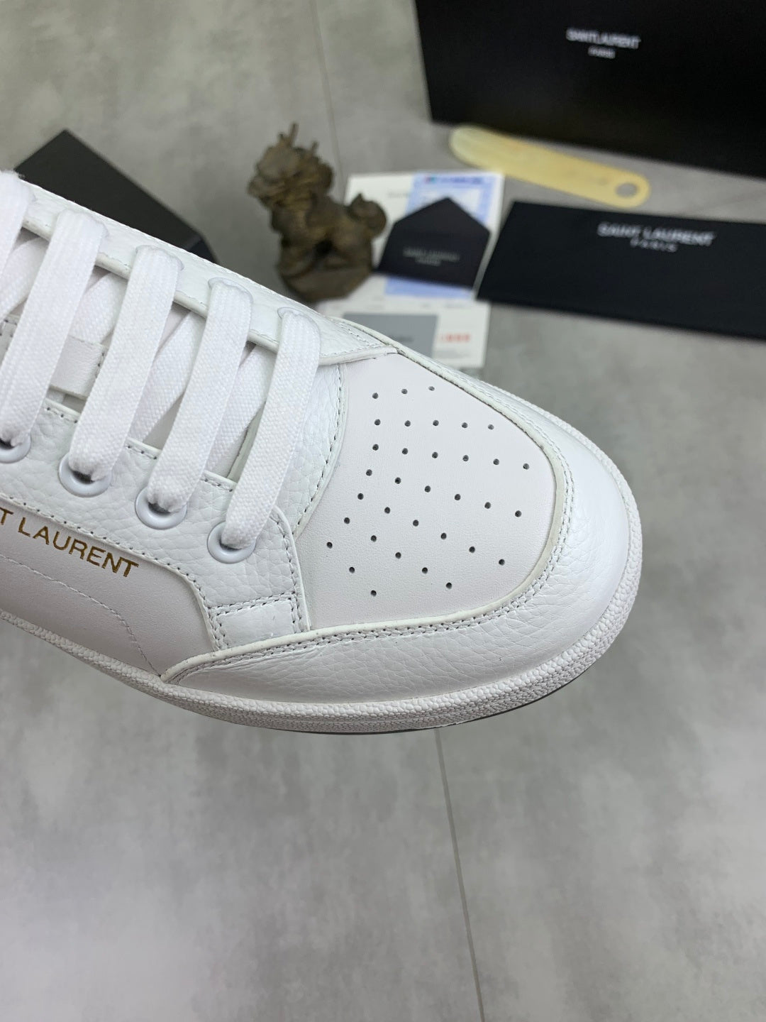 White unisex sneaker with perforated quarter panel and white lace-up closure