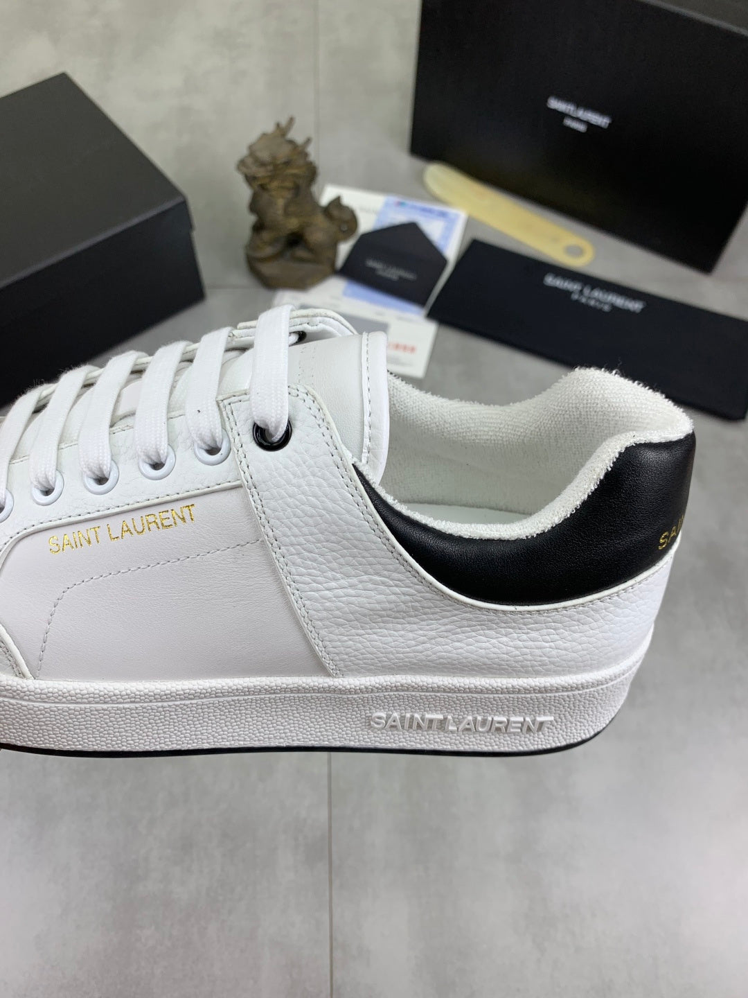 White unisex sneaker with black collar lining and "SAINT LAURENT" side detail