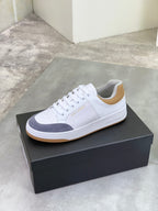 White and navy low-top sneakers with gum sole, lace-up style