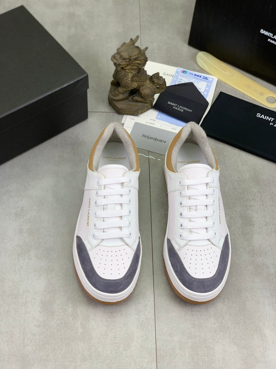Pair of white low-top sneakers with navy panels, lace-up and gum rubber soles