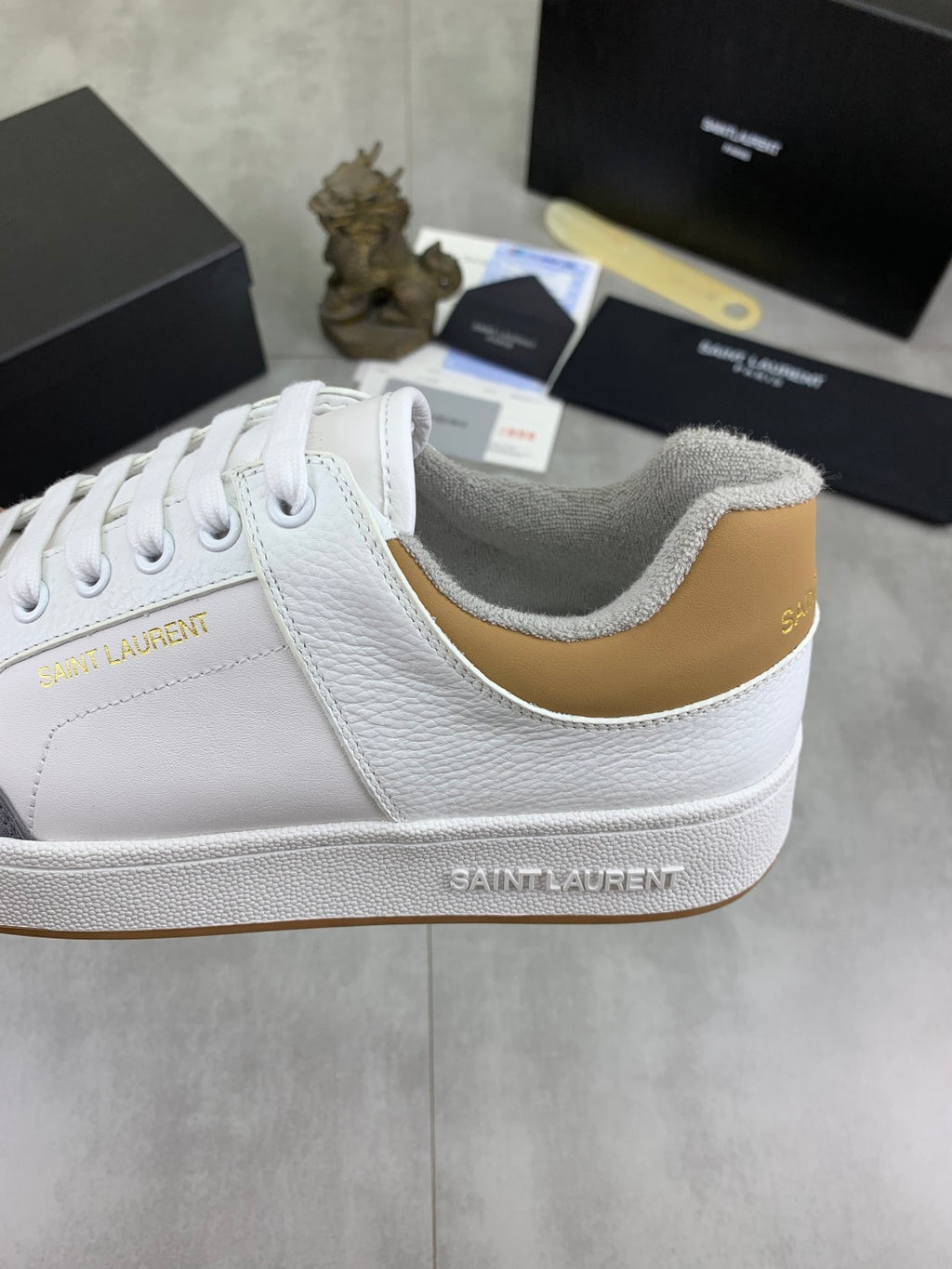 White leather sneakers with gold-toned collar trim and Saint Laurent branding