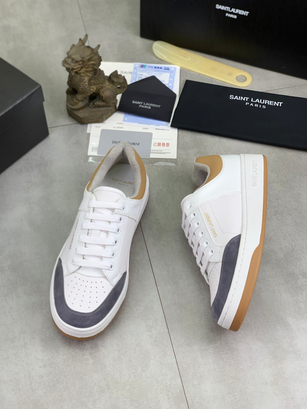 White lace-up sneakers with navy side panel and tan rubber sole