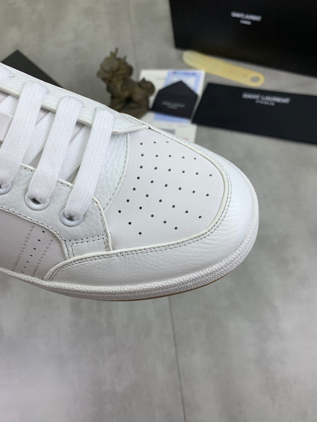 Close-up of white perforated leather sneaker toe with white laces