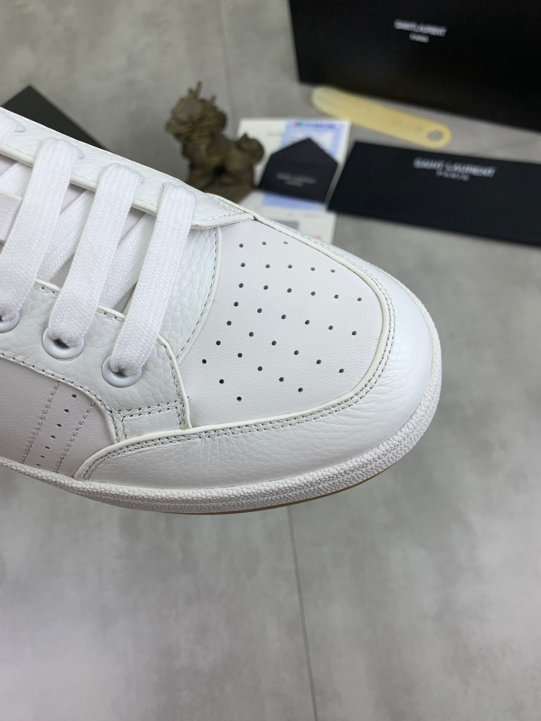 Close-up of white perforated leather sneaker toe with white laces