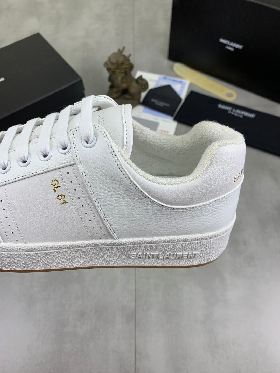 Close-up of white sneaker side with embossed trim and embroidered "SAINT LAURENT"