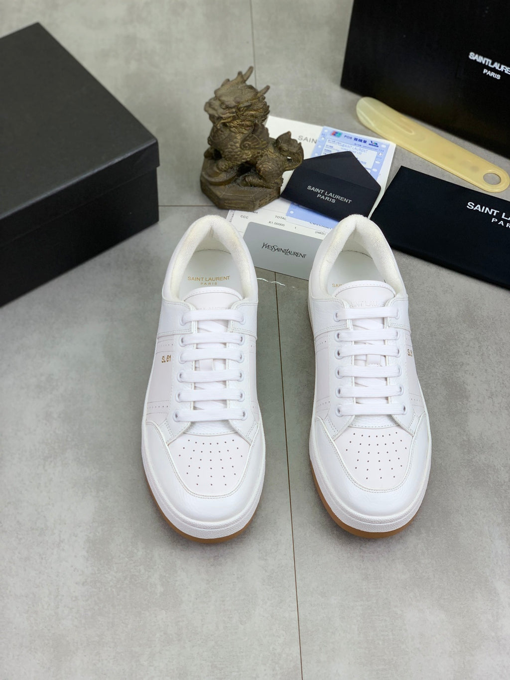 Pair of white lace-up sneakers with perforated toe and gum outsole