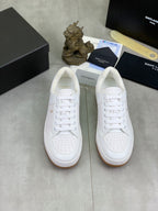 Pair of white lace-up sneakers with perforated toe and gum outsole