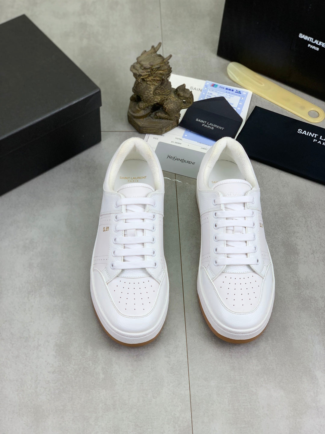 Pair of white lace-up sneakers with perforated toe and gum outsole