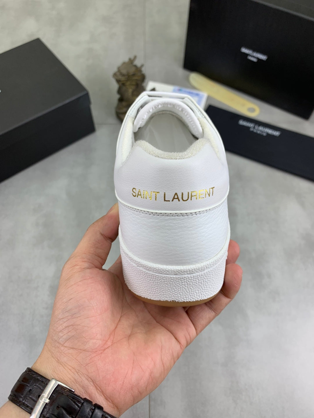 Back view of white lace-up sneakers with "SAINT LAURENT" logo on heel