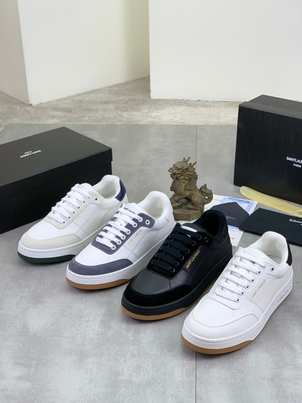 Three low-top leather sneakers: white, dark navy/black, and off-white with white soles