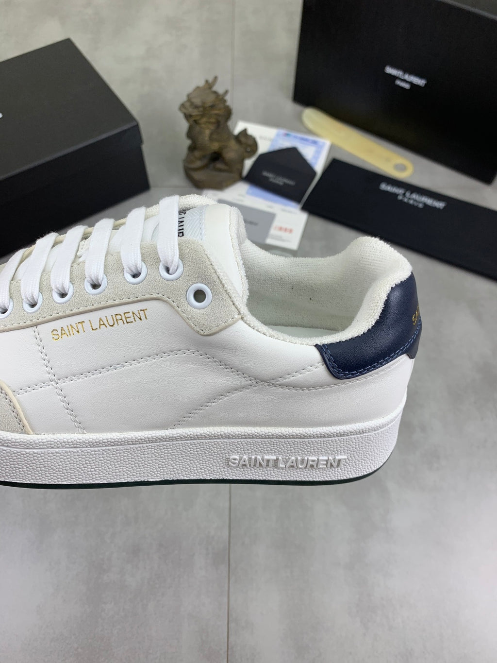 Off-white leather sneaker with Saint Laurent branding and navy collar panel