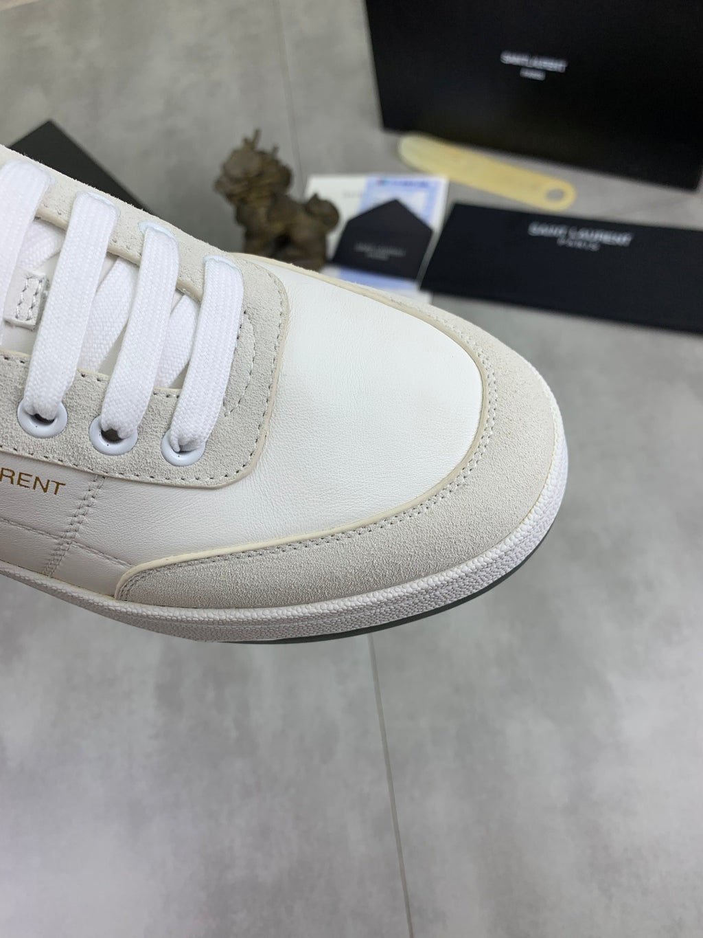 Off-white leather sneaker side panel with white laces and light stitching